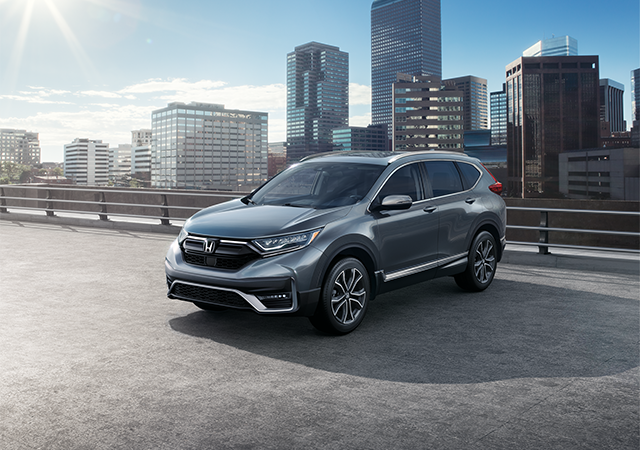 Front passenger-side view of the 2021 CR-V Touring in Modern Steel Metallic, driving across a bridge.